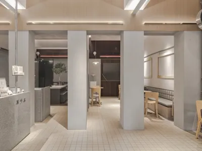 明亮溫馨的餐廳空間，設有餐桌、椅子與盆栽，並包含配有冰箱與水槽的廚房
