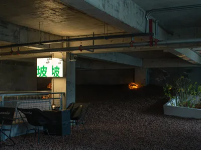 Dimly lit indoor space with a concrete floor, two chairs, and a dining table
