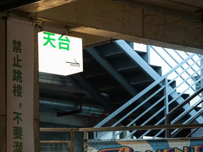 A vintage metal sign in front of a concrete staircase, possibly leading to an underground area, with a sense of exploration and discovery
