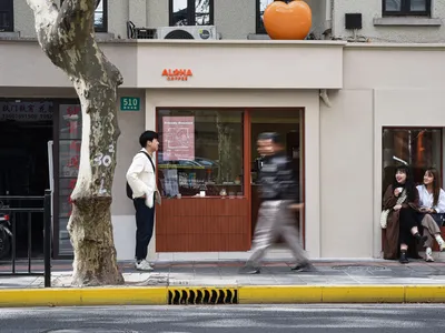 A restaurant with a wooden exterior, featuring a mix of brown and white tones, with people walking and dining inside