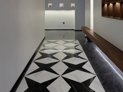 A clean and organized hotel lobby with a black and white checkered tile floor, two benches, and three clocks on the wall