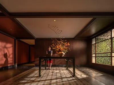 A cozy lobby with a wooden floor, a dining table, chairs, and a vase, creating a comfortable and inviting atmosphere