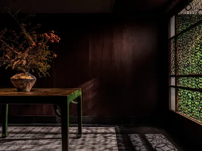 溫馨客廳配木桌、棕色牆面與花瓶插花，兩把椅子營造溫暖氛圍