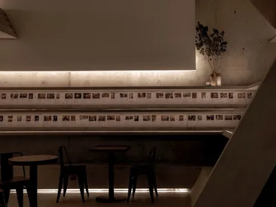 Modern restaurant with a long counter, chairs, and artwork on the walls, creating a minimalist atmosphere