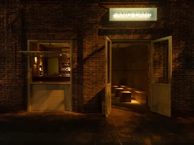 Cozy Asian restaurant with a brick wall, wooden door, and bottles on display, blending modern and traditional design elements