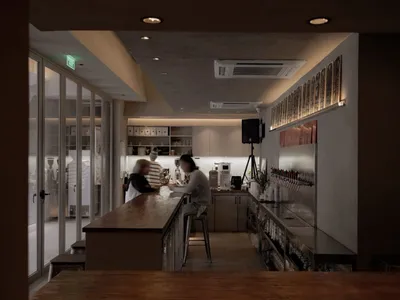 A casual restaurant bar area with patrons enjoying their time together, featuring a counter with bottles, cups, and bowls, and a refrigerator in the background