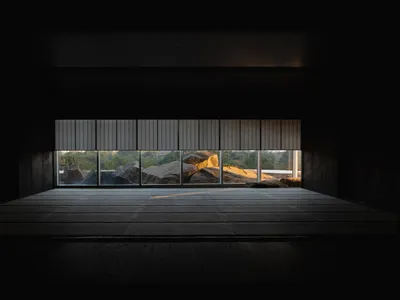 Empty living room with large windows offering a view of rocks outside, receiving natural light