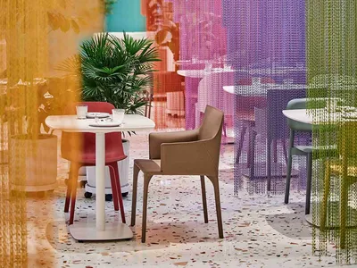 A modern restaurant interior with a dining area, bar, and colorful curtains, surrounded by potted plants