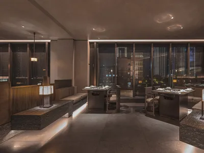 A modern restaurant with a large window, multiple tables, and chairs, creating an inviting and comfortable atmosphere for dining
