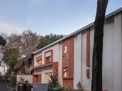 一座橘色建築、白屋頂、大窗戶的飯店，周圍環繞盆栽植物與人群