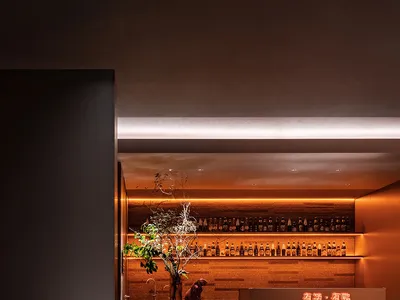 餐廳內溫馨的酒吧區，擺放酒瓶、酒杯，背景有餐桌