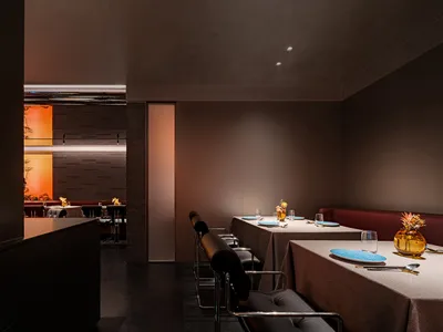 A modern restaurant dining area with tables, chairs, and wine glasses, set up for guests to enjoy their meals in a stylish and inviting atmosphere