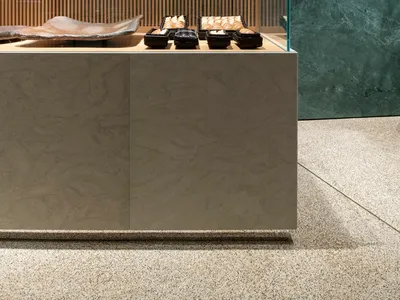 A glass display case in a store showcases neatly arranged cakes, donuts, and pastries, creating an inviting atmosphere