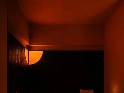 Cozy restaurant space with an orange-lit room, black walls, and a dining table with chairs and decorative items