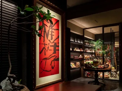 A bustling Asian restaurant with a red Chinese character painting on the wall, surrounded by bowls and bottles, suggesting a variety of traditional dishes and ingredients