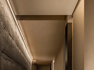 A clean and well-maintained hotel hallway with a white tile floor, two doors on either side, and a neutral color scheme