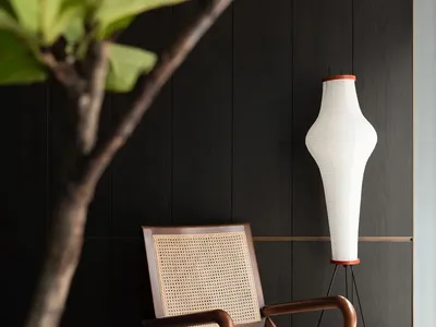 A cozy living area with a wooden chair, two potted plants, and a vase, creating a warm and inviting atmosphere