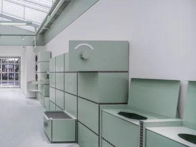 綠牆綠地板工業風廚房，配備各式家電與碗盤，用於食物準備，整潔有序的空間
