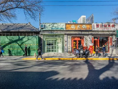 A bustling Asian restaurant on a city street corner with a red building and green accents, surrounded by pedestrians and motorcycles