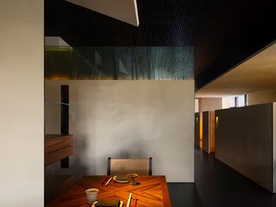An empty dining area in a restaurant with a wooden table and chairs, two bowls and spoons on the table, suggesting the restaurant is closed