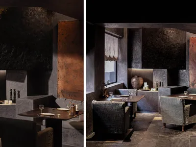 Dimly lit dining and lounge space with wine glasses, vases, and a couch near a window