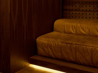 Cozy living space with a wooden wall, a leather couch, and soft lighting from wall-mounted lamps