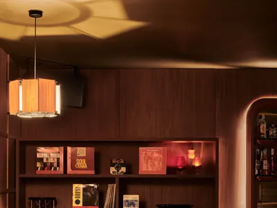 Cozy living space with wooden walls and floors, featuring books, bottles, and a warm atmosphere