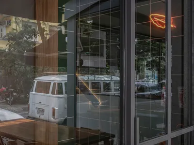 A well-lit restaurant interior with wooden tables, metal accents, and various items on the tables, set against a backdrop of a glass door and natural light
