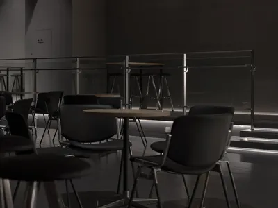 A dark and moody restaurant with several tables and chairs, well-organized and inviting, but empty and lacking natural light