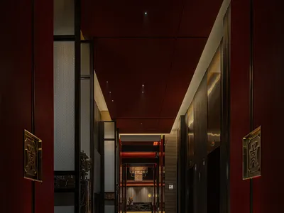 Empty hotel hallway with red walls, two doors, and a calm atmosphere