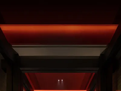 A luxurious hotel hallway with a red ceiling, stone wall, and black door, creating a sophisticated atmosphere