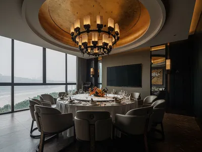 A dining area with a round table set with various items, surrounded by chairs, in a room with a gold ceiling and sophisticated ambiance