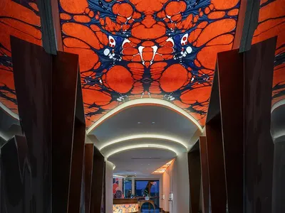 擁有鮮豔橘色天花板、牆上掛畫，以及中央附近鳥類雕像的華麗飯店走廊