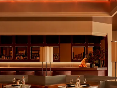 一間舒適的餐廳，設有長餐桌與椅子、酒杯和杯子，背景環繞著沙發