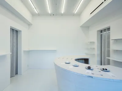 極簡風格的廚房餐廳空間，採用白色表面、大型料理台，以及水槽與冰箱，營造出乾淨明亮的氛圍