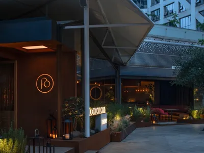 夜晚的餐廳外觀，棕色立面搭配盆栽植物與露台區，營造放鬆氛圍