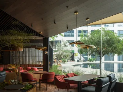 Modern restaurant interior with a dining area, bar, and potted plants, featuring clean lines and minimalistic design elements, with dim lighting creating a cozy atmosphere