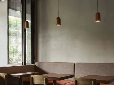 A modern restaurant interior with gray walls, dim lighting, and a cozy atmosphere, featuring a dining area with tables, chairs, and benches