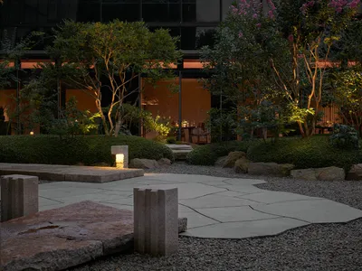 A nighttime patio scene with a dining table, chairs, and potted plants creating a cozy atmosphere for socializing or al fresco dining