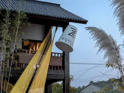 A photo of a cozy house with a wooden exterior, featuring a dining table and two chairs, with a white cup hanging on its side