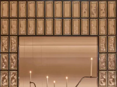 A sophisticated dining space with a large mirror, gold frame, and multiple lit candles creating a warm and inviting atmosphere