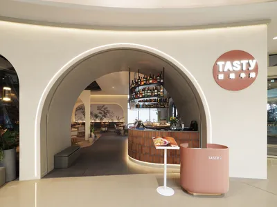 Modern restaurant interior with a bar area, potted plants, and a collection of bottles on shelves behind the counter