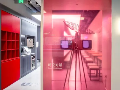 Cozy modern restaurant interior with a pink accent wall, TV, and chairs in a dining area