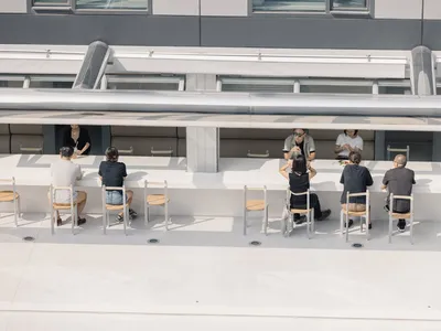 A casual dining area with multiple tables and chairs, featuring a social atmosphere with people gathered to enjoy meals together