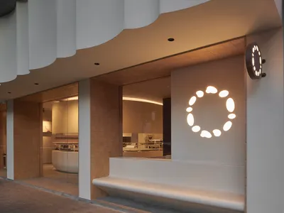Inviting restaurant with a bench seating area near a window, counter with sink and oven, and two refrigerators