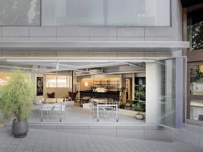 現代餐廳內部，設有吧台區、餐桌與盆栽，白色灰色牆面與頂部燈光