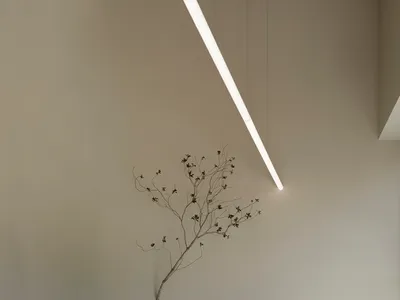 寧靜而溫馨的客廳空間，配有白色沙發、兩把椅子，以及牆上的布質樹雕塑，營造溫暖舒適的氛圍