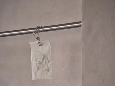 一間髒亂的浴室，配有衛生紙架和兩卷衛生紙，牆壁上明顯有汙漬