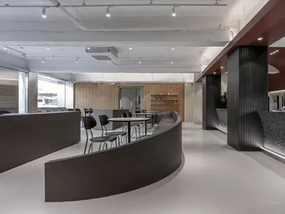 開放式餐廳內部，弧形設計結合木質與金屬元素，設有椅子與餐桌，營造現代而溫馨的氛圍
