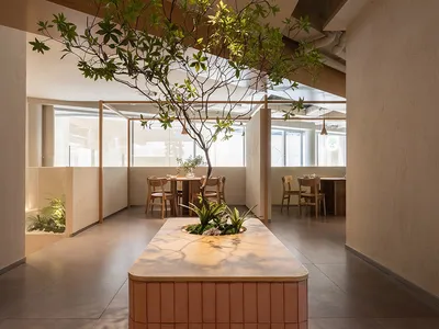 現代餐廳內部，設有大型餐桌、盆栽與水泥牆，營造溫馨氛圍